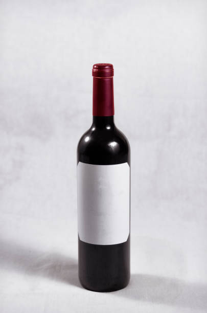istock Bottle of dark red wine, red cap and white label without letters or marks 1282841167