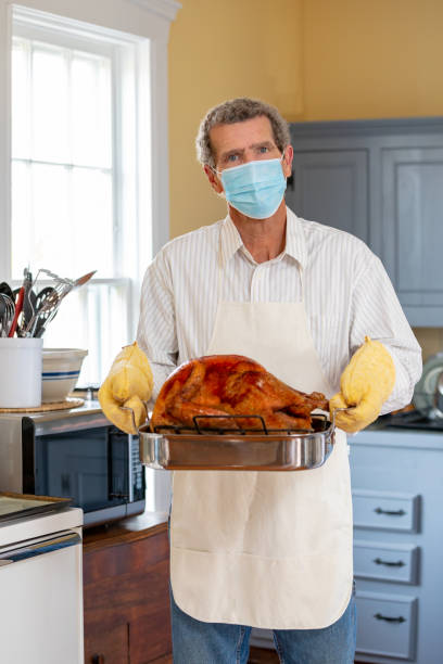 Mature Adult Man Holding Thanksgiving Turkey Wearing COVID-19 Face Mask Mature Adult Man Holding Thanksgiving Turkey Wearing COVID-19 Face Mask thanksgiving holiday covid stock pictures, royalty-free photos & images