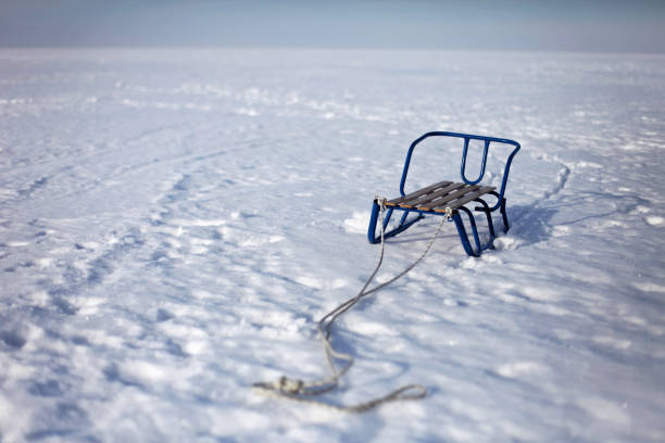 A child sledge staying on the snow in the middle of the frozen lake, happy wintertime, winter family lifestyle