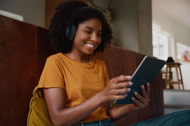 istock Young african woman relaxing at home watching video on digital tablet at home 1282846830