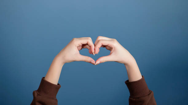 istock Gesturing female hand on blue background. heart shape 1282846872