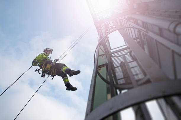 Manual rope access technician - worker abseil from tower - antenna in sun beams stock photo
