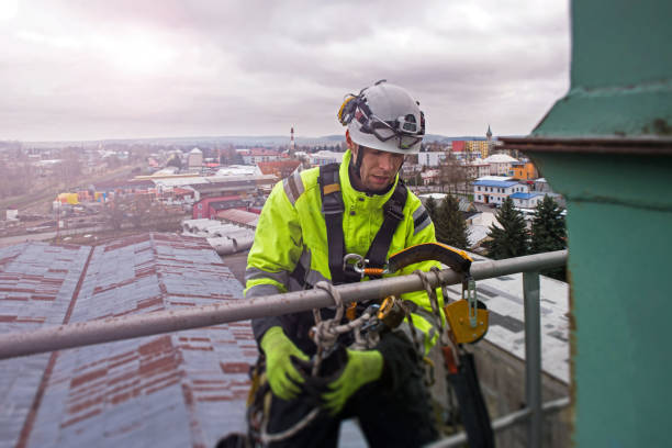 istock Manual rope access technician - worker abseil from tower - antenna with town behind him 1282848323