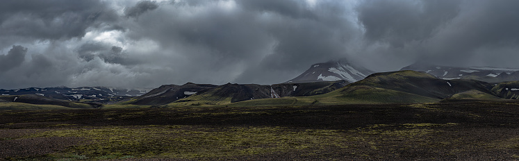 A wide panorama shot of a cloudy overcast rugged landscape.