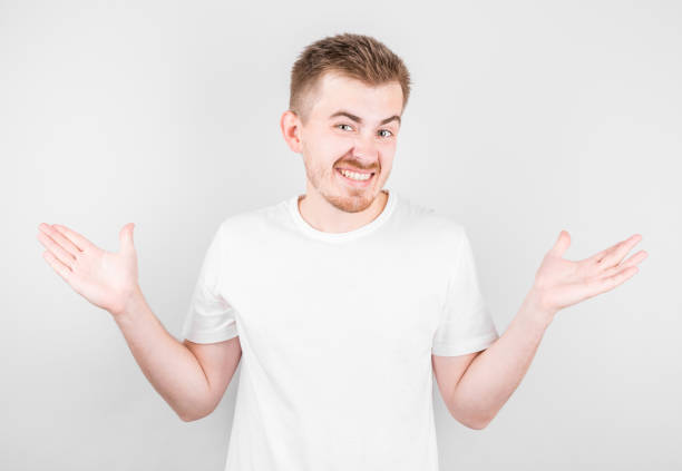 istock Shrugging man in white t-shirt looking at camera 1282855485
