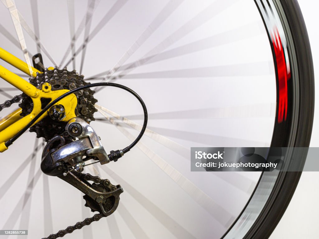 Details of a rear detailleur at the rear wheel of a race bike with spokes in motion blur Bicycle Chain Stock Photo