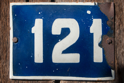 Weathered grunge square metal enameled plate of number of street address with number 121