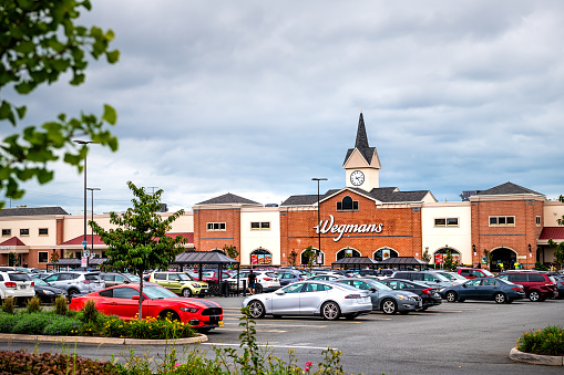 Sterling, USA - September 12, 2020: Wegmans grocery store by parking lot with tower architecture and many cars in northern Virginia
