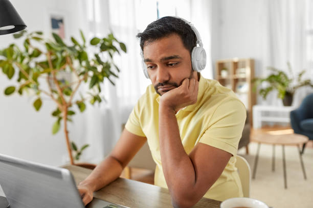 istock man in headphones with laptop working at home 1282858295