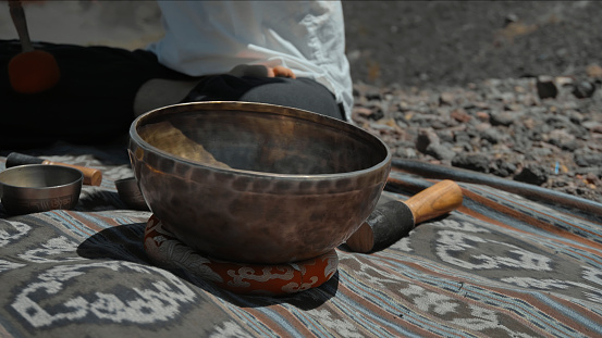 A young Asian guy playing Tibetan singing copper cups on a viewing mountain in nature