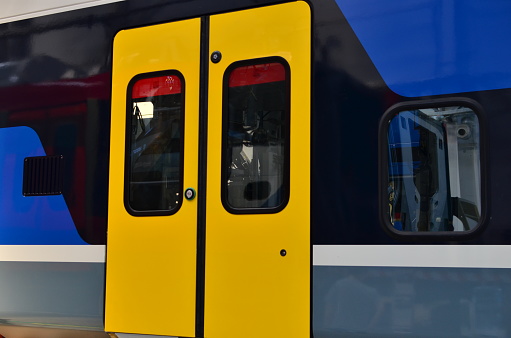 View on wagon of the high speed train with yellow door closed in the rail station. Electric button for press to open sliding mechanical door at a railway  platform.