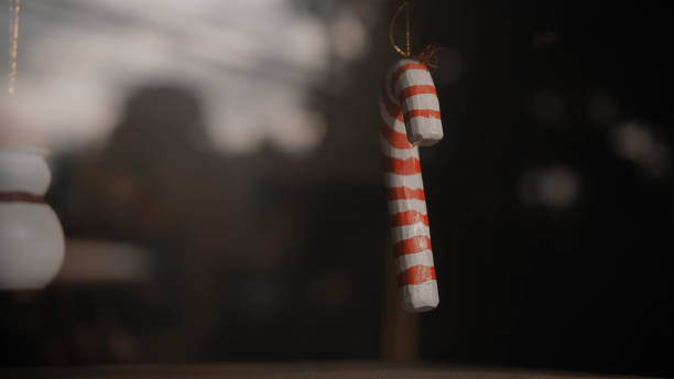istock Christmas decorations candy cane hanging on a thread behind the glass in the house 1282864048