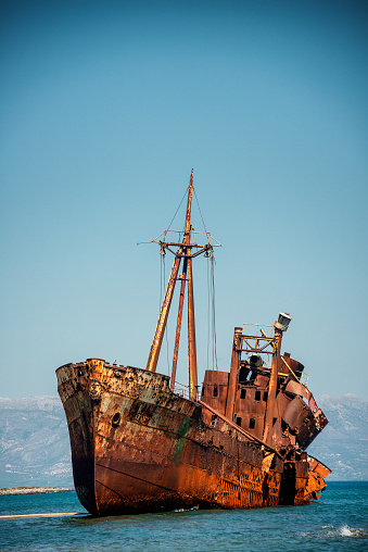 Dimitrios shipwreck in Gythio, Greece. A partially sunk rusty metal shipwreck decaying through time on a sandy beach on a sunny day. Famous shipwreck in greece