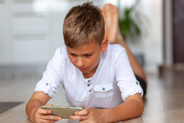 istock Little boy watching something on cell phone while relaxing on floor at home. 1282866726
