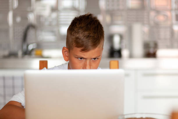 istock Serious little boy watching something over laptop at home. 1282866759