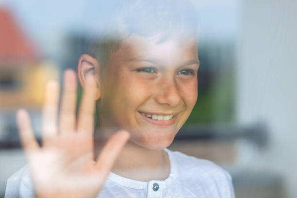 istock Happy little boy day dreaming while looking through window during home quarantine. 1282866798