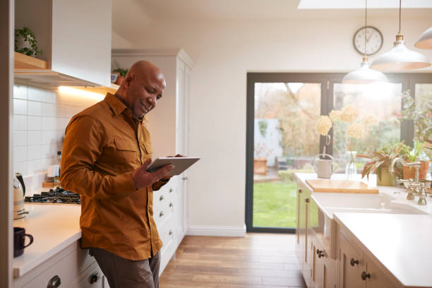 istock Mature Man At Home In Kitchen Looking At Digital Tablet 1282867553