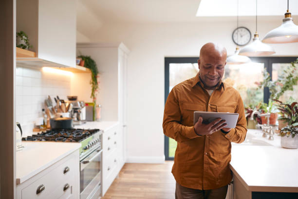 istock Mature Man At Home In Kitchen Looking At Digital Tablet 1282867677