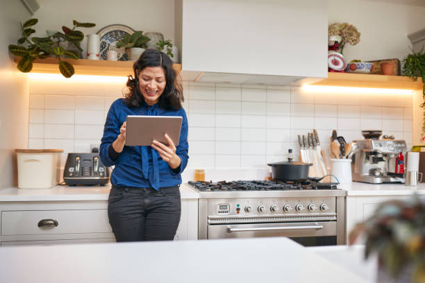 istock Mature Woman At Home In Kitchen Looking At Digital Tablet 1282867726