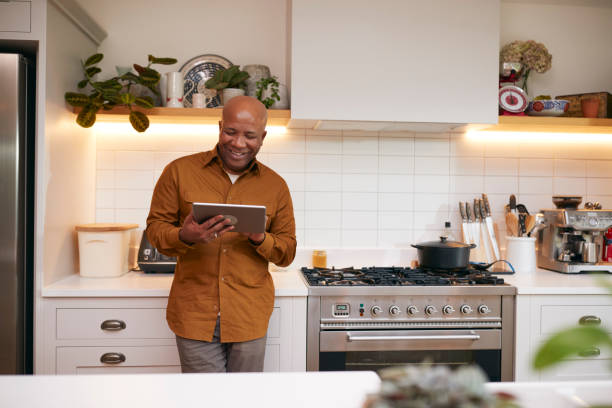 istock Mature Man At Home In Kitchen Looking At Digital Tablet 1282867879