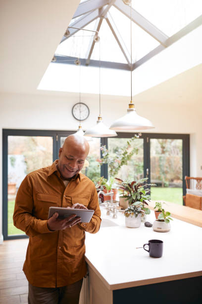 istock Mature Man At Home In Kitchen Drinking Coffee And Looking At Digital Tablet 1282868073