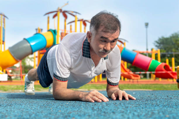 hombre asiático maduro está haciendo ejercicio de tablón en el gimnasio al aire libre cerca del parque - body care asian ethnicity body building toughness fotografías e imágenes de stock