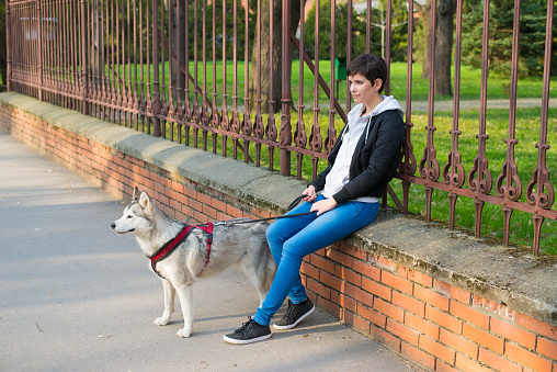 Young woman walking pet dog in the city.