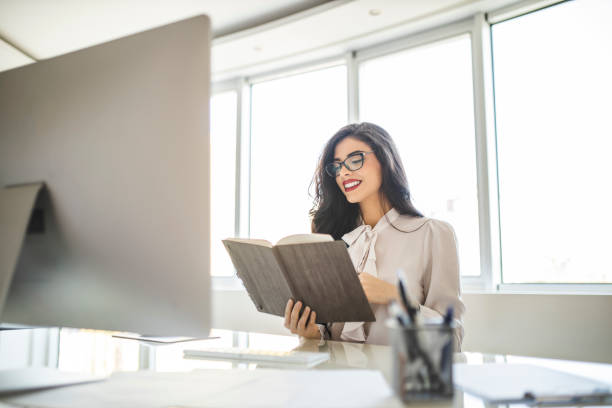 istock Young business woman reading diary, panning the day and working on computer in her office 1282876421