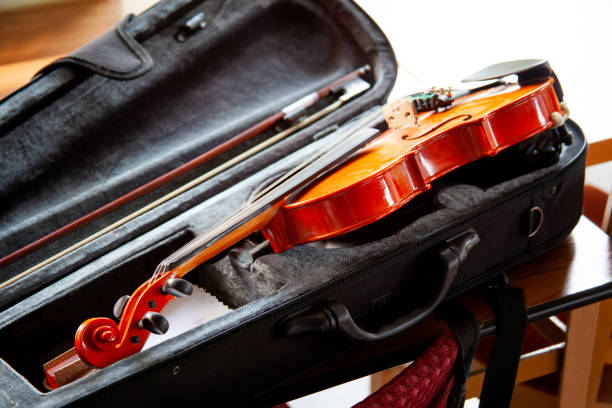 istock Violin with a bow laying in an open black fiddle case on the table. Classical musical string instruments group concept, nobody. Safe instrument storage for travelling 1282877281
