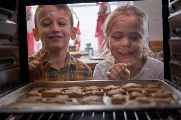 istock Little Kids Baking Gingerbread Cookies in the Oven 1282879559