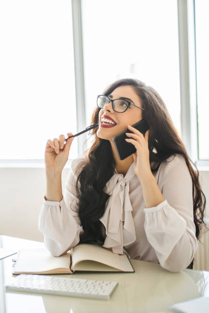 istock Portrait of beautiful young woman using her smart phone, reading documents and working in her office 1282880236