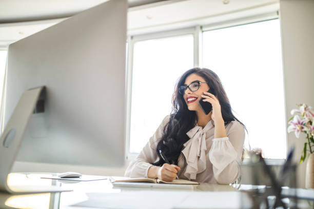 istock Portrait of beautiful young woman using her smart phone, reading documents and working in her office 1282880565