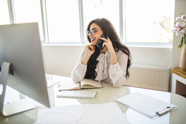 istock Portrait of beautiful young woman using her smart phone, reading documents and working in her office 1282880879