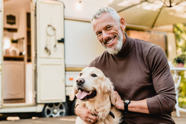 istock Handsome grey-haired mature man hugging his dog in the caravan yard 1282881573