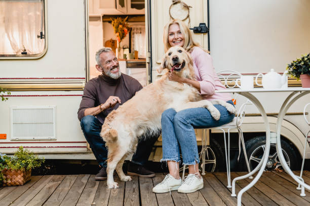 foto di famiglia di una coppia caucasica matura che gioca con il loro retriever nella porta della roulotte - hiking mature adult women senior adult foto e immagini stock