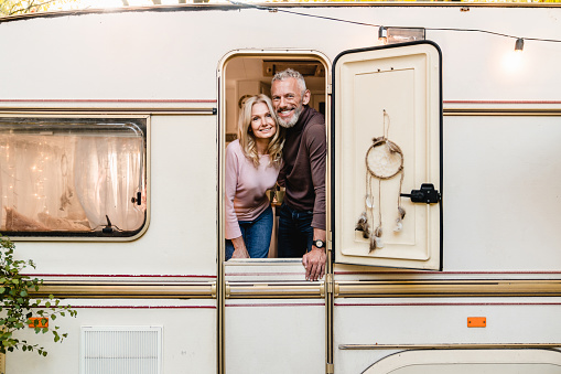 Cheerful happy elderly couple standing on the porch of their motor home