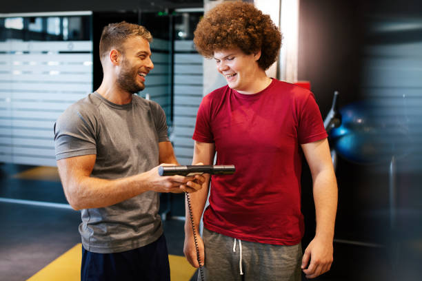istock Overweight young man exercising gym with personal trainer 1282884563