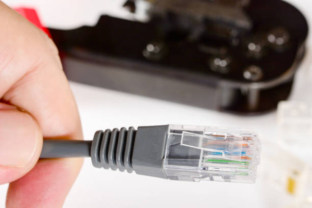 istock Engineer's hand holds patch cord with RJ45 connector and crimping tool for home Internet connection. Home network concept, close up. 1282890281