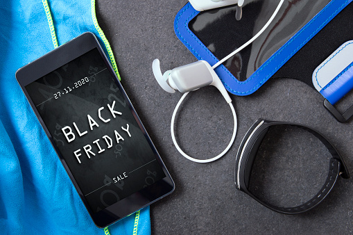 Smartphone with black friday banner lying on the stone slab with sport accessory
