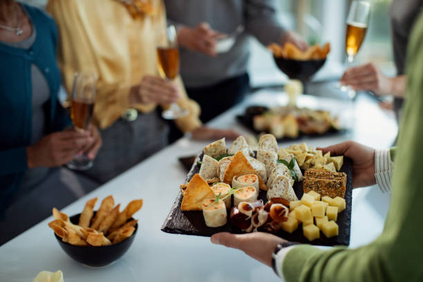 Close-up of businessman serving food on office party. Close-up of businessman bringing food while having party in the office with his coworkers. office parties stock pictures, royalty-free photos & images