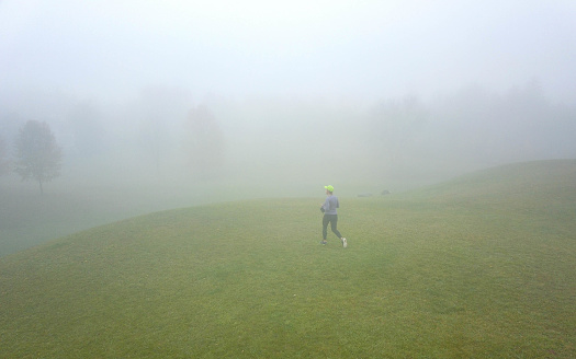 Woman is running on a foggy morning
