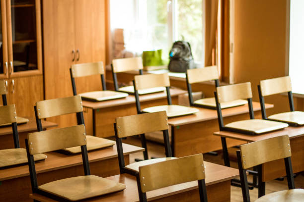 istock Empty school class, wooden chairs stand on the desk 1282893718