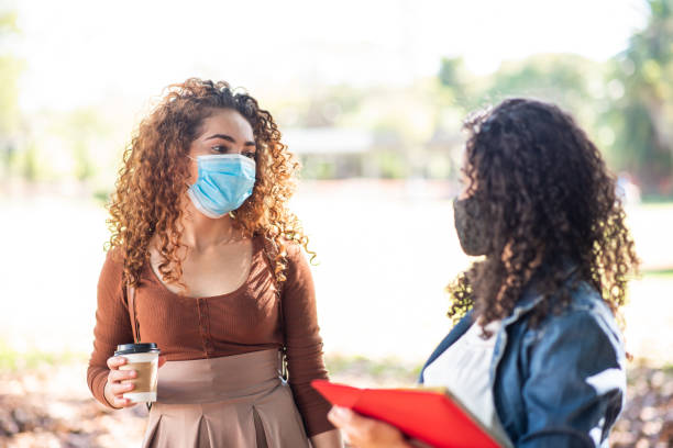 istock Two young student people talking on the university campus. Back to school wearing face protection mask 1282897157