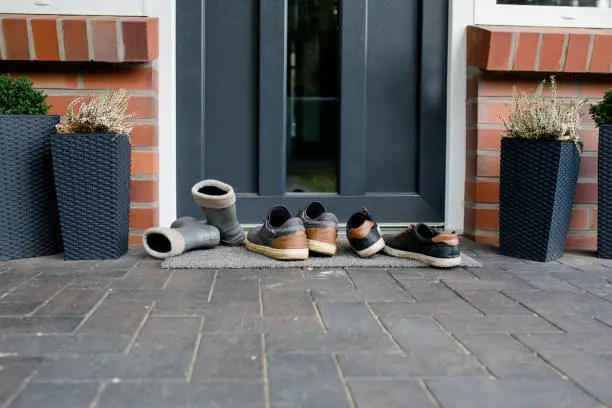 three pairs of shoes stand in front of the front door