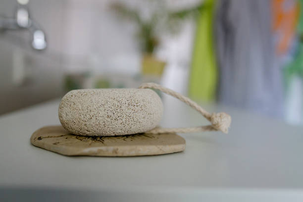 Pumice stone lies on a stone pad. There is a plant in the background