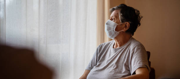 istock Senior woman wearing protective face mask and looking through window 1282903158