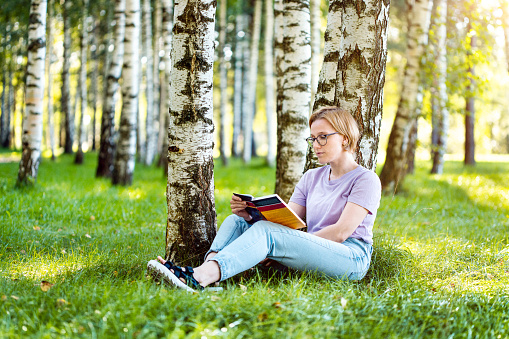 Reading a book in calm birch grove
