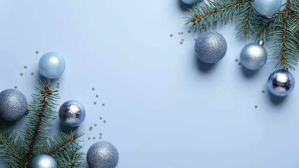 istock Happy holidays postcard template. Christmas tree branches decorated blue and silver balls on paste blue background. Christmas, New Year, winter holiday celebration concept. 1282904373