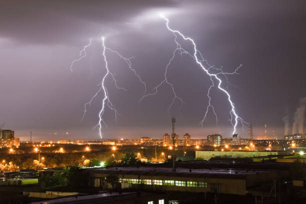 istock Powerful flash lightning hitting the city at night over dark gray sky. A strong lightning strike over hits the ground, illuminating the industrial area around. 1282907247