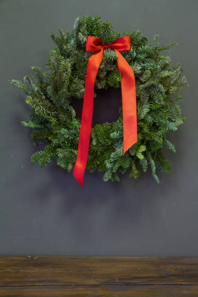 istock Stylish minimalistic christmas fir branches wreath with red bow on gray background, copy space, greeting card 1282908126